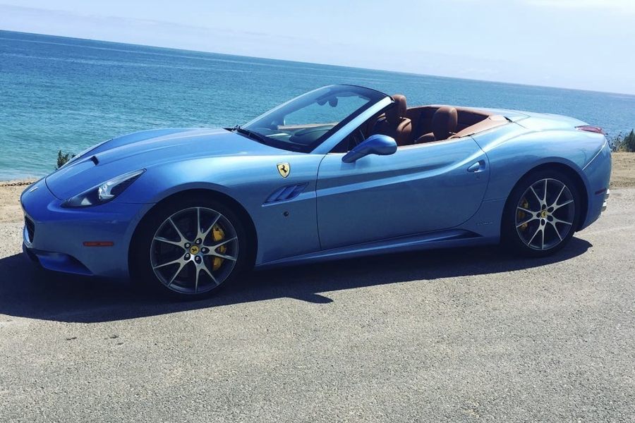 Light blue Ferrari California convertible parked beside the Pacific Ocean